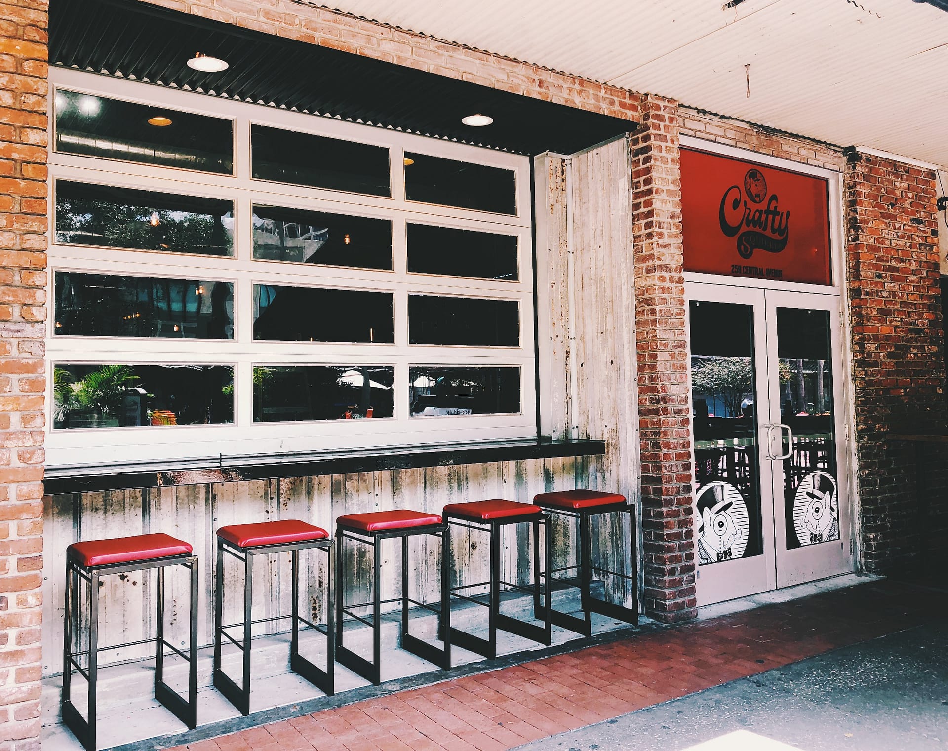 The outside bar, complete with red stools and garage doors at Crafty Squirrel in Downtown, St. Petersburg, FL